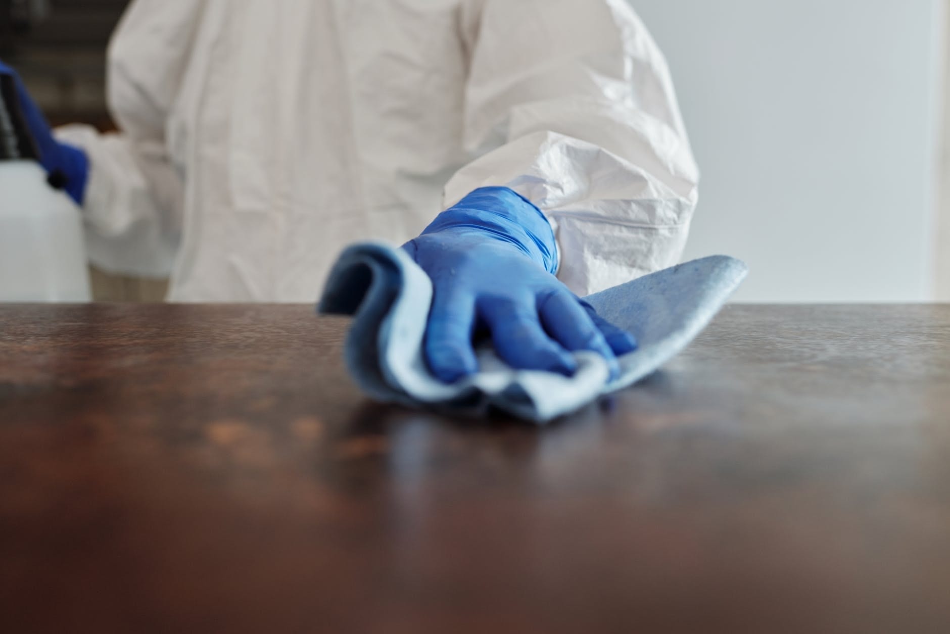 person in white cleaning suite, blue gloves and cleaning