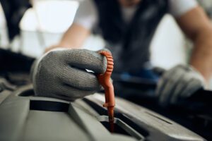 Close-up of auto repairman checking car oil in at car workshop.