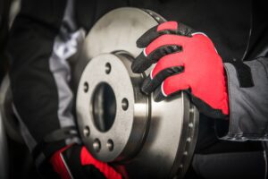 Modern Ventilated Car Brake Disc in Mechanics Hands. Automotive Theme.